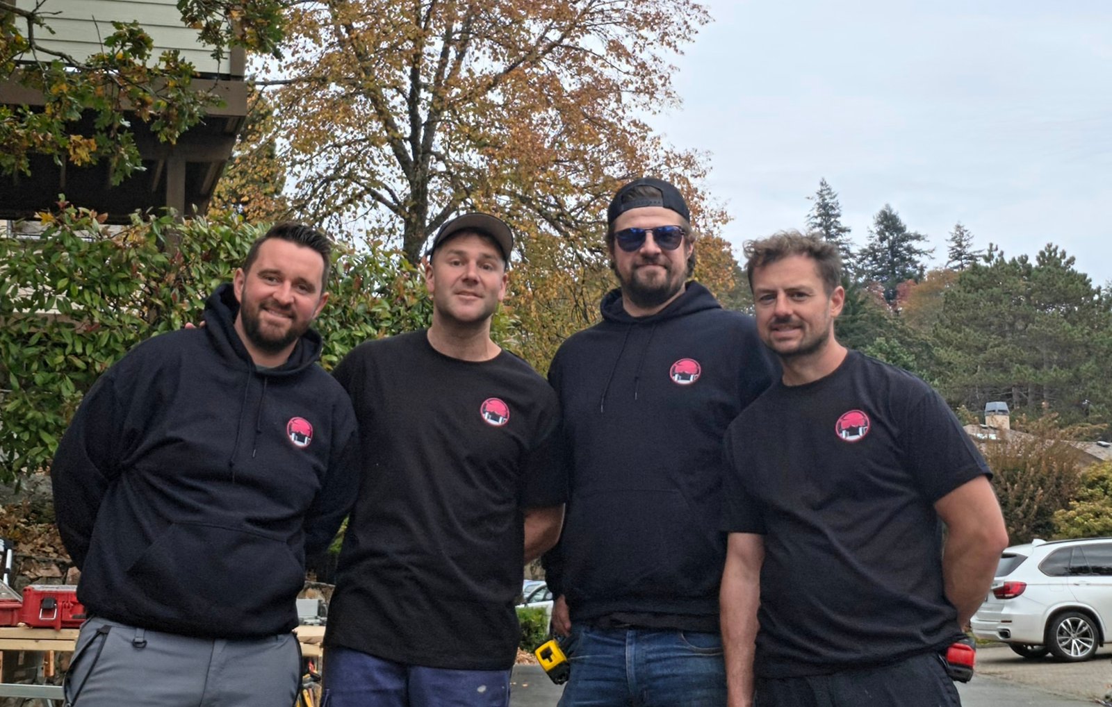 The Dynamic Fencing and Decks team wearing black shirts and hoodies with pink company logos