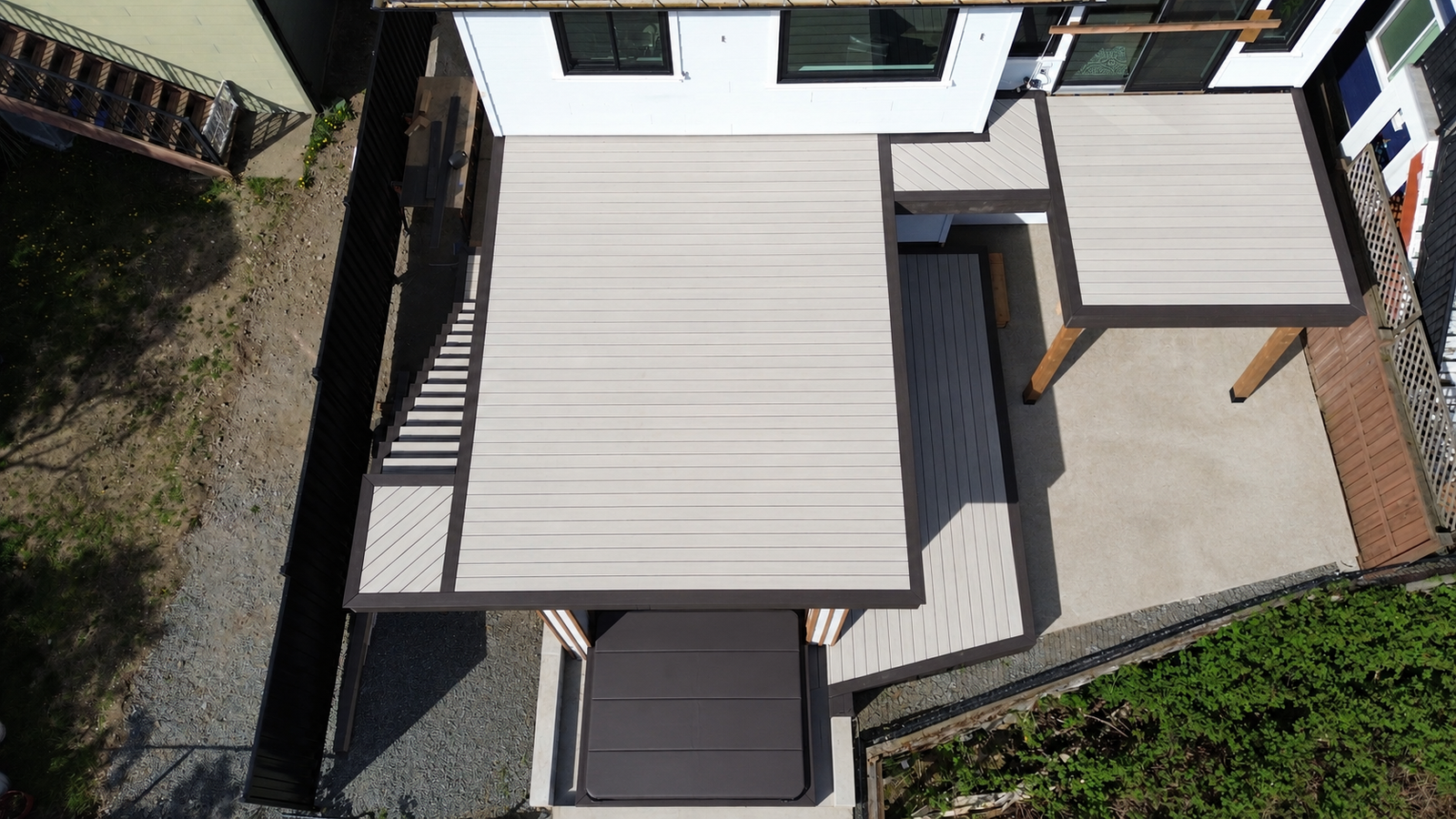 Aerial view of a multi-level deck with contrasting borders, stairs and a covered hot tub