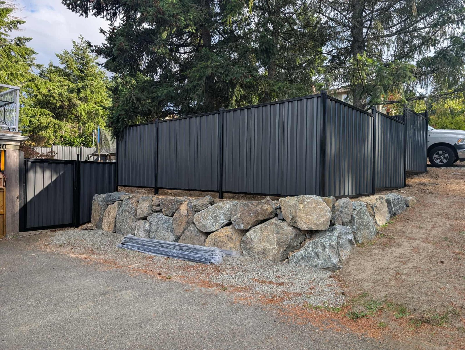 Dark metal privacy fence above a stone retaining wall
